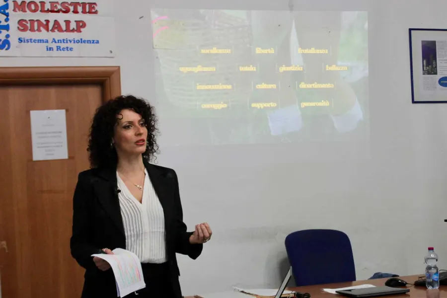 Una relatrice parla durante un incontro, sullo schermo le parole dei nostri valori